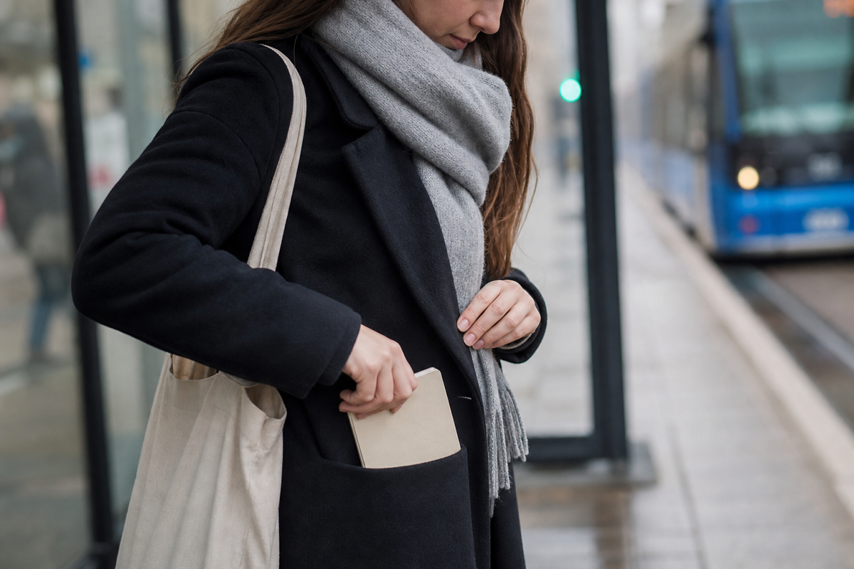 Student håller en liten almanacka vid en hållplats